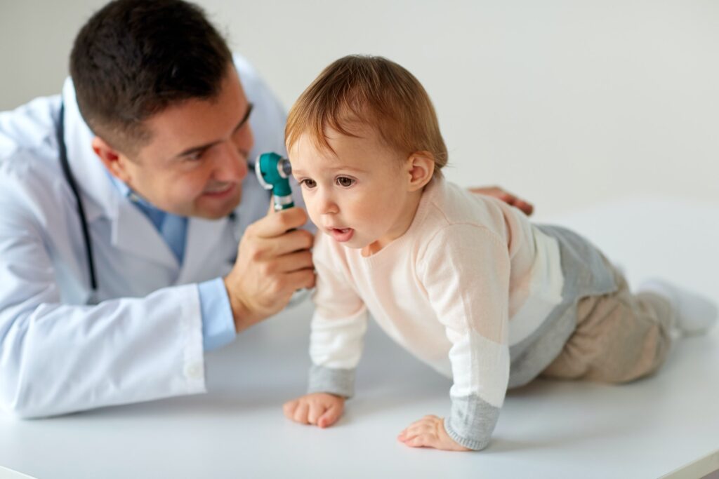 doctor with otoscope checking baby ear at clinic